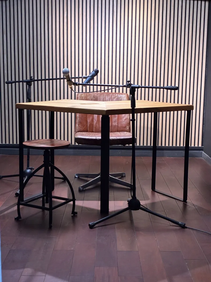 Le plateau podcast : table en chêne, deux micros sur pied et mur acoustique